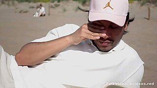 A man lounging on the beach is approached by a woman who gives him a sensual experience