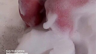 A blonde mature with huge natural tits masturbates in the foam bath