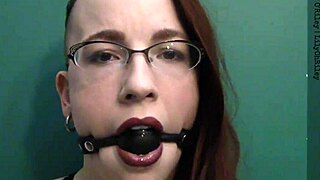 Close up of a redhead wearing a ball gag and drooling with desire
