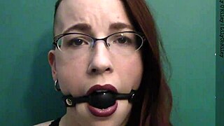 Close up of a redhead wearing a ball gag and drooling with desire