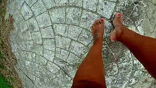 African pornstar walks barefoot on public beach, dirtying feet in fetish fun.