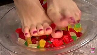 a kinky brunette sticks her feet in gummy bears and performs a footjob until cumshot
