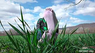 Goddess spreads curly feet in white socks on spring grass field
