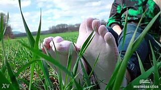 Goddess spreads curly feet in white socks on spring grass field