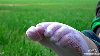 Goddess spreads curly feet in white socks on spring grass field