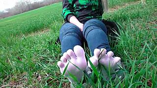 Goddess spreads curly feet in white socks on spring grass field