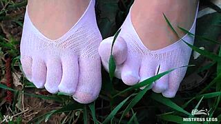 Goddess spreads curly feet in white socks on spring grass field
