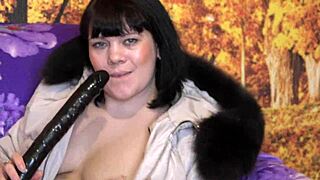 A mature woman in a fur-trimmed hood sucks a large dildo passionately.