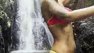 monika fox parades pink top yellow shorts through steamy jungle waterfalls