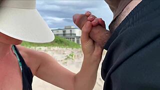 A milf jerks off a stranger on a public beach for a bet