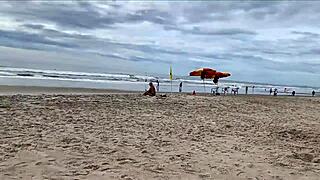 A milf jerks off a stranger on a public beach for a bet