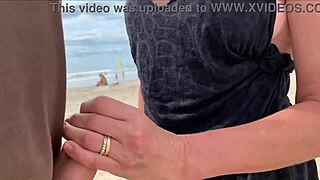 A milf jerks off a stranger on a public beach for a bet